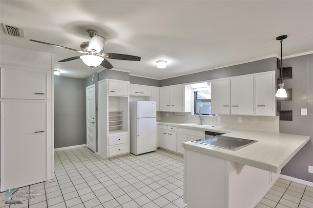 kitchen featuring kitchen peninsula, decorative backsplash, white refrigerator, decorative light fixtures, and white cabinetry