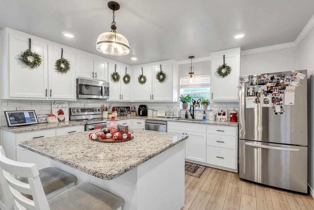 kitchen featuring white cabinetry, stainless steel appliances, and decorative light fixtures