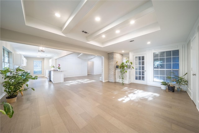 unfurnished living room with a tray ceiling and light wood-type flooring