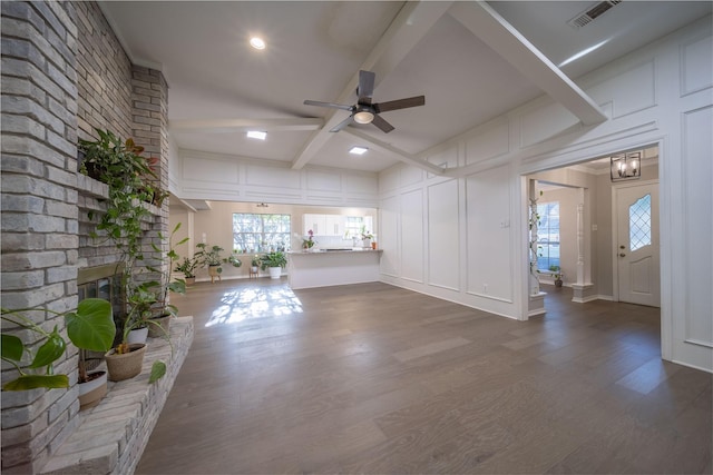 unfurnished living room with hardwood / wood-style flooring, a fireplace, a healthy amount of sunlight, and beamed ceiling