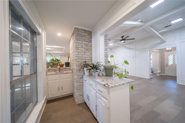 kitchen featuring light stone countertops, ceiling fan, dark hardwood / wood-style floors, kitchen peninsula, and white cabinets