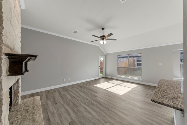 unfurnished living room with lofted ceiling, crown molding, ceiling fan, light wood-type flooring, and a fireplace