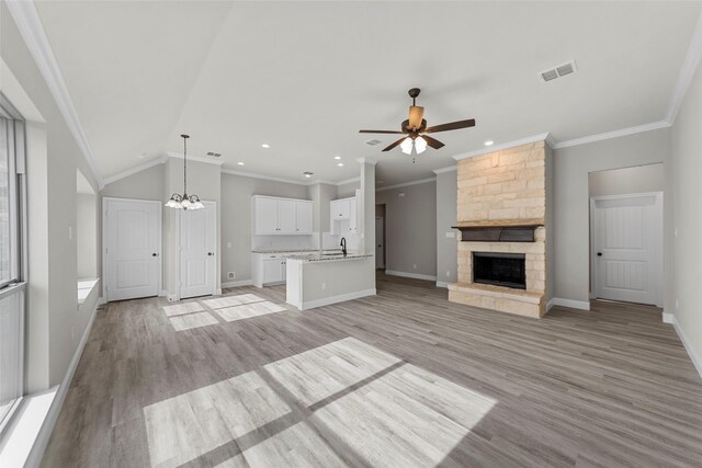 unfurnished living room with a fireplace, lofted ceiling, light hardwood / wood-style floors, and crown molding