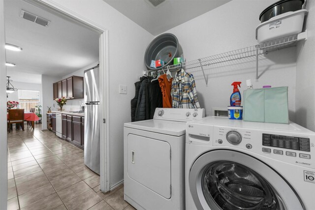 laundry area with sink, separate washer and dryer, and light tile patterned flooring