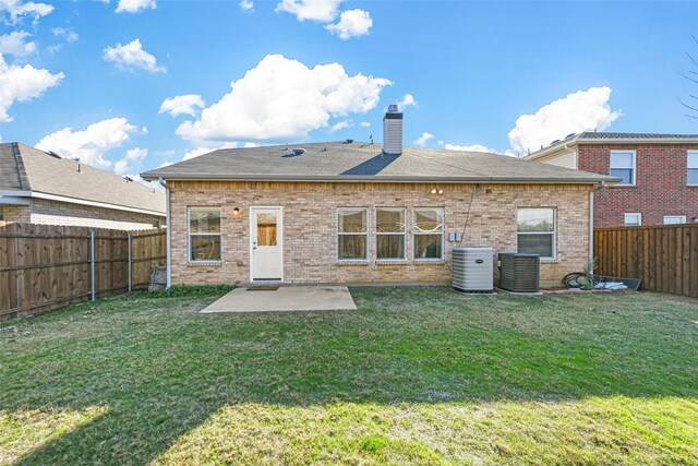 rear view of property with a yard, a patio, and central air condition unit