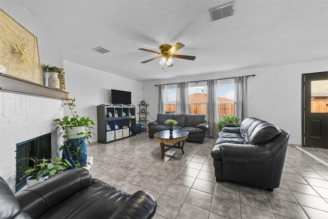 tiled living room with a fireplace, a textured ceiling, and ceiling fan