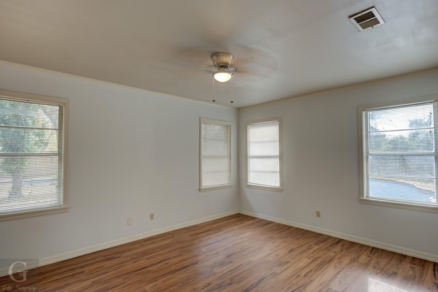 empty room featuring a wealth of natural light, ceiling fan, and hardwood / wood-style flooring