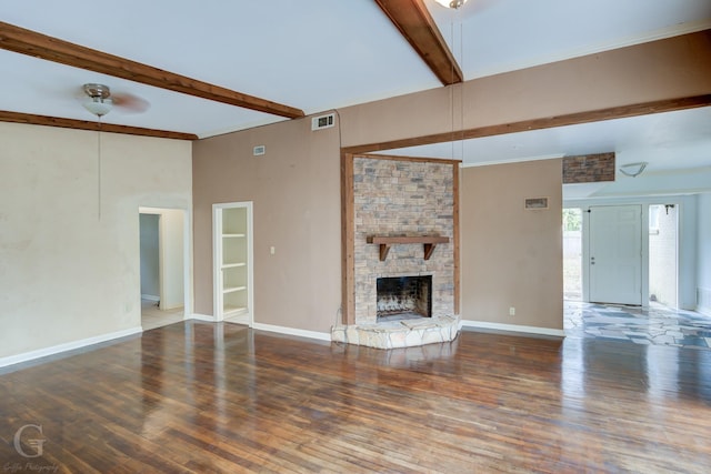 unfurnished living room with ceiling fan, beam ceiling, dark hardwood / wood-style flooring, and a fireplace