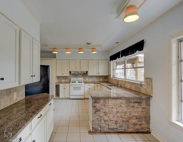 kitchen featuring backsplash, dark stone countertops, white range with gas stovetop, and sink