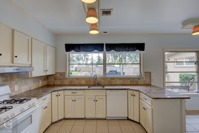 kitchen featuring white appliances, backsplash, a wealth of natural light, and sink