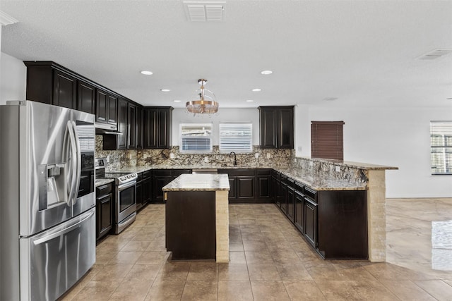 kitchen featuring sink, light stone counters, decorative light fixtures, a kitchen island, and appliances with stainless steel finishes