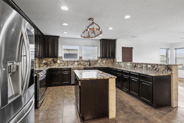 kitchen with backsplash, a textured ceiling, stainless steel appliances, sink, and a kitchen island