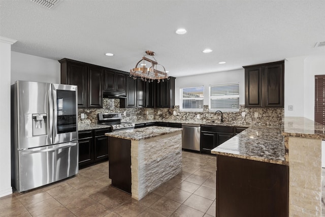 kitchen featuring light stone countertops, sink, stainless steel appliances, backsplash, and kitchen peninsula