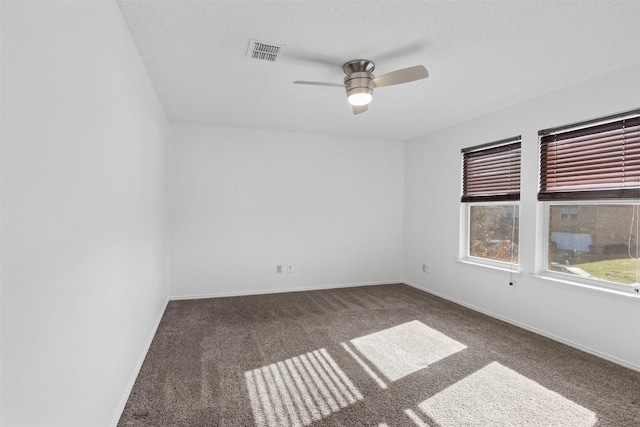 empty room with dark colored carpet, ceiling fan, and a textured ceiling