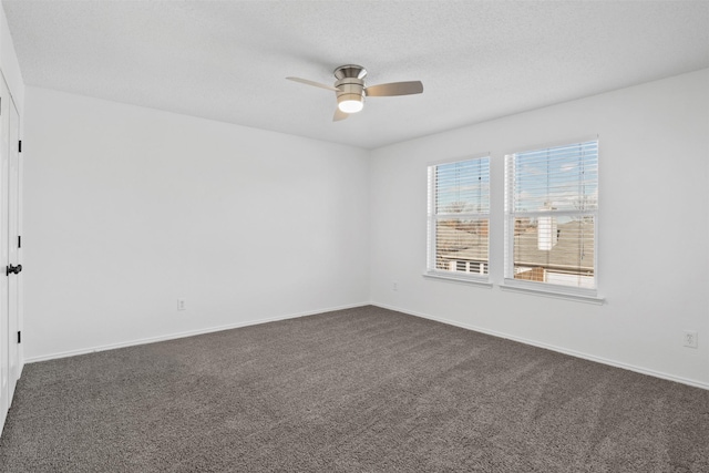 empty room with dark colored carpet, ceiling fan, and a textured ceiling