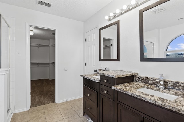 bathroom featuring tile patterned flooring, a textured ceiling, and an enclosed shower