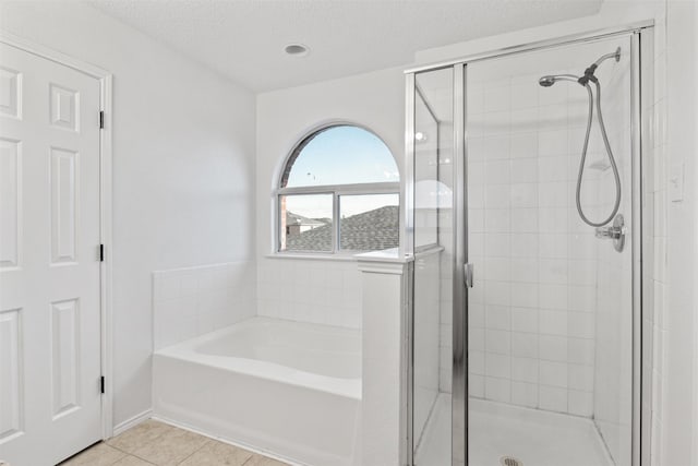 bathroom with separate shower and tub, tile patterned flooring, and a textured ceiling