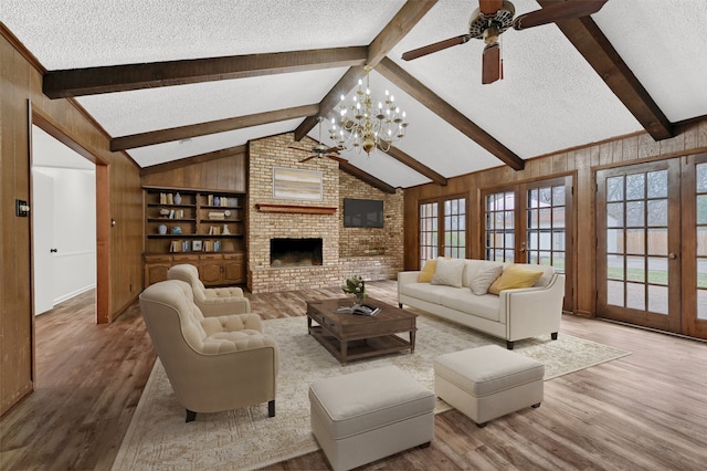 living room featuring french doors, lofted ceiling with beams, wood-type flooring, a textured ceiling, and a fireplace