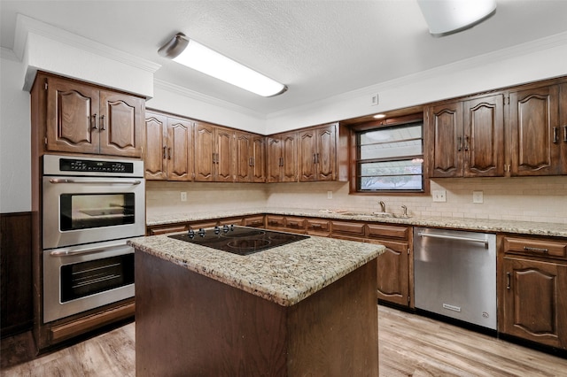 kitchen featuring sink, a center island, light stone counters, stainless steel appliances, and light hardwood / wood-style flooring