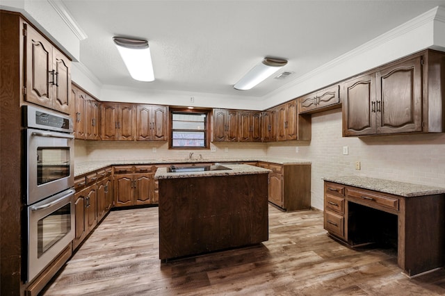 kitchen with wood-type flooring, a center island, crown molding, and double oven