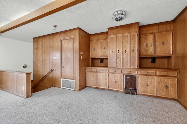 unfurnished living room featuring light carpet, a textured ceiling, and wood walls