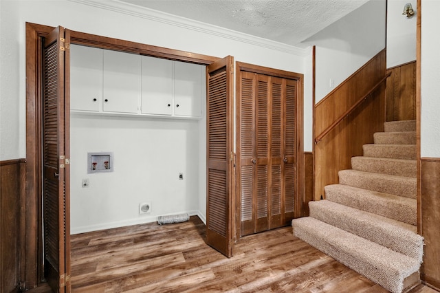 clothes washing area featuring cabinets, wood-type flooring, a textured ceiling, hookup for a washing machine, and electric dryer hookup