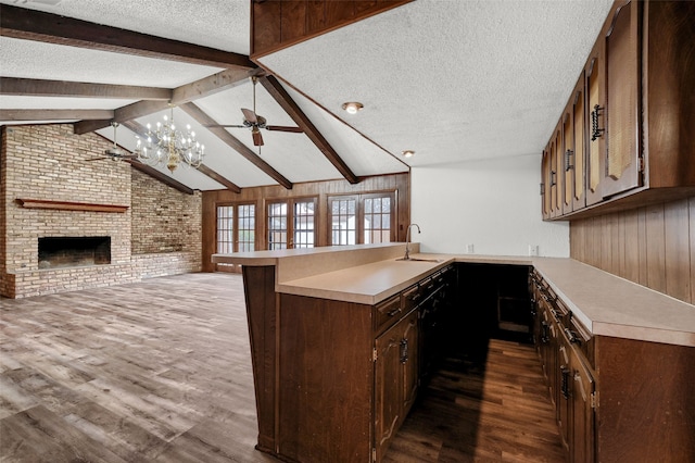 kitchen featuring a kitchen bar, a brick fireplace, a textured ceiling, dark hardwood / wood-style flooring, and kitchen peninsula