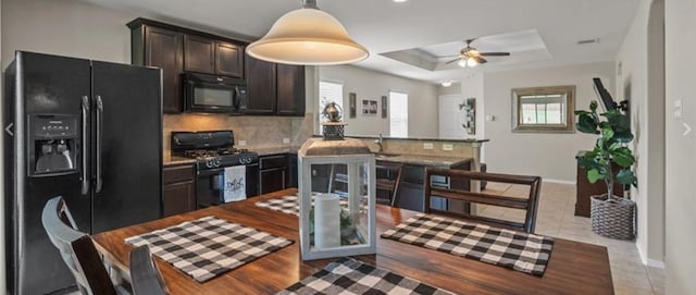 kitchen with black appliances, dark brown cabinets, a healthy amount of sunlight, and a raised ceiling