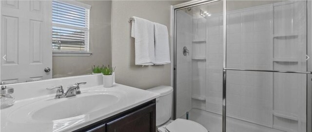 bathroom with vanity, toilet, and a shower with door