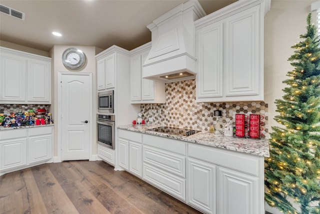 kitchen featuring premium range hood, appliances with stainless steel finishes, white cabinetry, dark hardwood / wood-style flooring, and light stone countertops