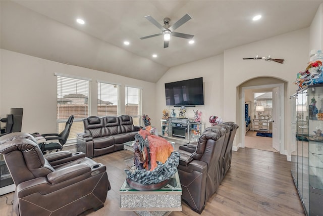 living room featuring a fireplace, light wood-type flooring, ceiling fan, and lofted ceiling