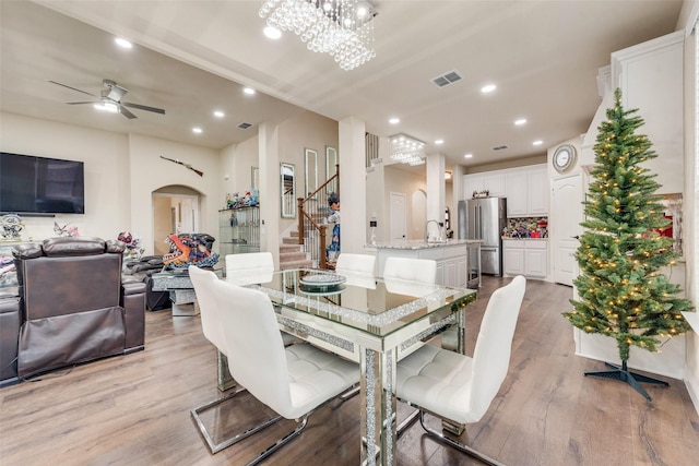 dining room with ceiling fan with notable chandelier, light wood-type flooring, and sink