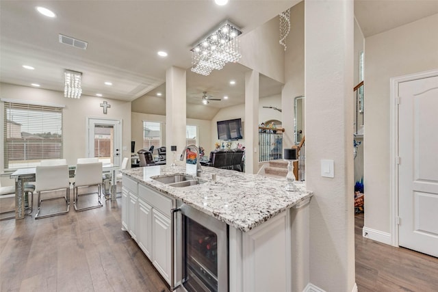 kitchen with ceiling fan, sink, beverage cooler, white cabinets, and hardwood / wood-style flooring