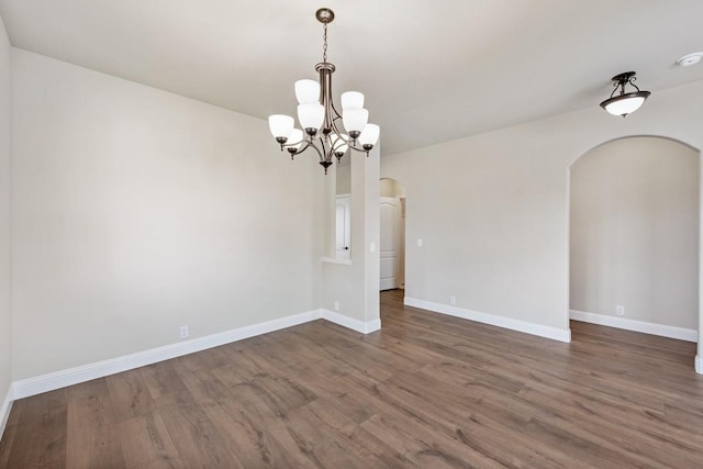 unfurnished room with a notable chandelier and dark hardwood / wood-style flooring