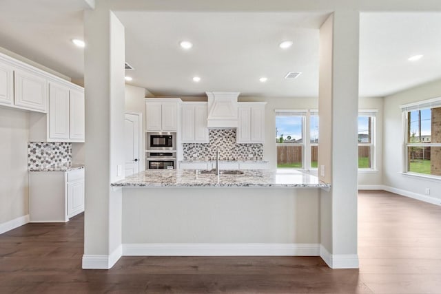 kitchen with sink, white cabinetry, stainless steel oven, light stone counters, and black microwave