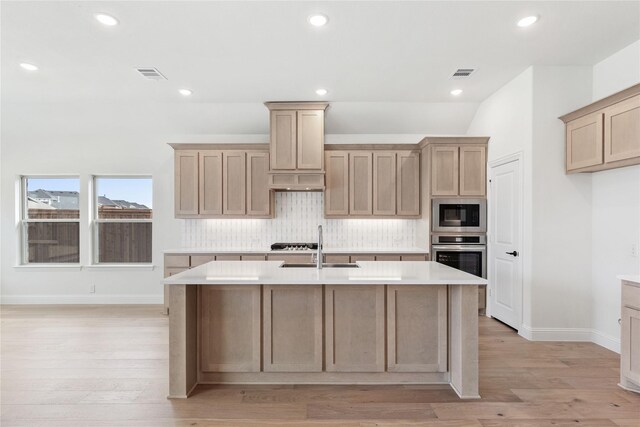 kitchen with dishwasher, sink, light hardwood / wood-style floors, a fireplace, and a center island with sink