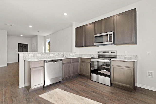 kitchen featuring kitchen peninsula, stainless steel appliances, dark hardwood / wood-style floors, light stone counters, and dark brown cabinetry