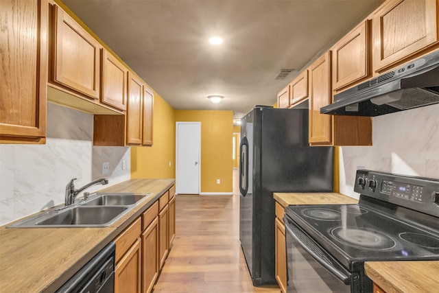 kitchen featuring tasteful backsplash, sink, light hardwood / wood-style flooring, and black appliances