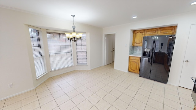 kitchen featuring backsplash, black fridge, light tile patterned floors, decorative light fixtures, and a chandelier