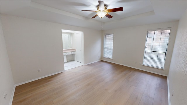 spare room featuring ceiling fan, light hardwood / wood-style floors, and a tray ceiling