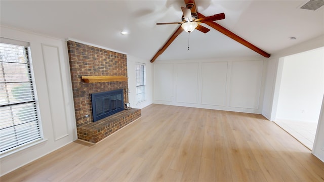 unfurnished living room with ceiling fan, light hardwood / wood-style floors, lofted ceiling with beams, and a brick fireplace