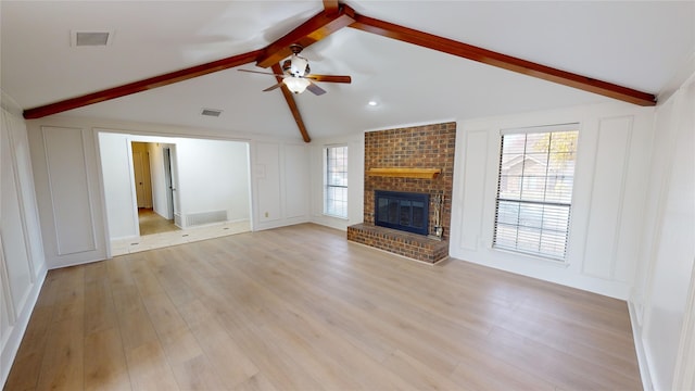 unfurnished living room with a brick fireplace, ceiling fan, lofted ceiling with beams, and light wood-type flooring