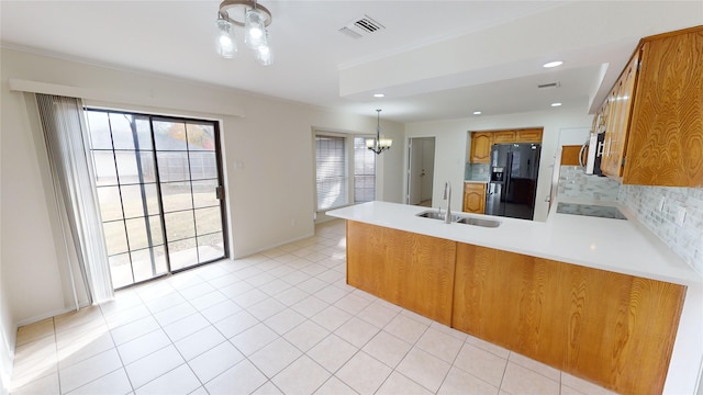 kitchen with sink, tasteful backsplash, kitchen peninsula, a chandelier, and black fridge with ice dispenser