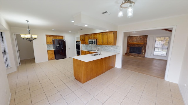 kitchen with sink, a notable chandelier, backsplash, kitchen peninsula, and black appliances