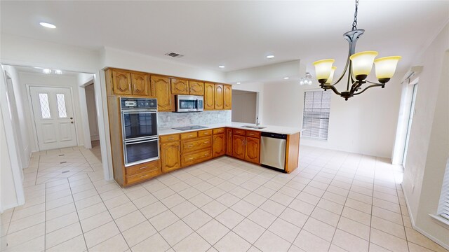 kitchen featuring backsplash, sink, black appliances, decorative light fixtures, and a chandelier