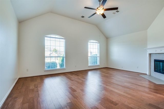 unfurnished living room with a tiled fireplace, ceiling fan, light hardwood / wood-style floors, and vaulted ceiling