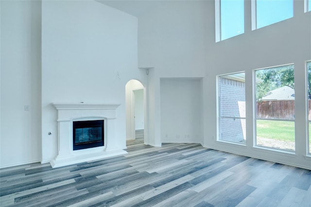 unfurnished living room featuring hardwood / wood-style floors and a towering ceiling