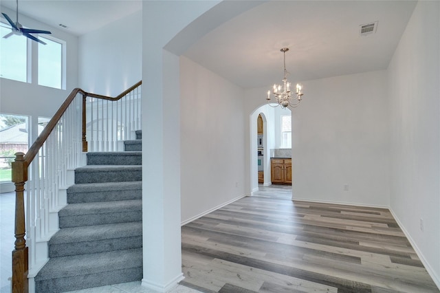 stairs featuring wood-type flooring and ceiling fan with notable chandelier