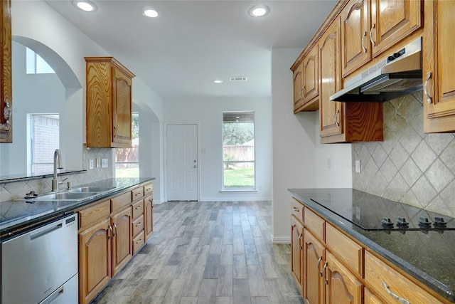 kitchen with light wood-type flooring, tasteful backsplash, black electric cooktop, dark stone countertops, and dishwasher