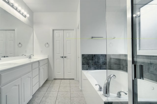 bathroom with double vanity, tile patterned floors, a sink, a garden tub, and a closet